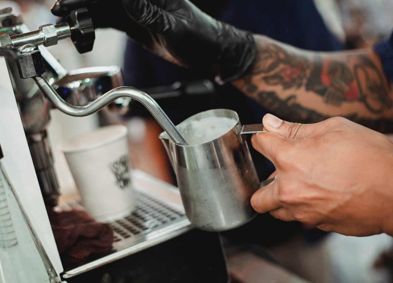 Barista parujące mleko z ekspresem do napoju kawowego.